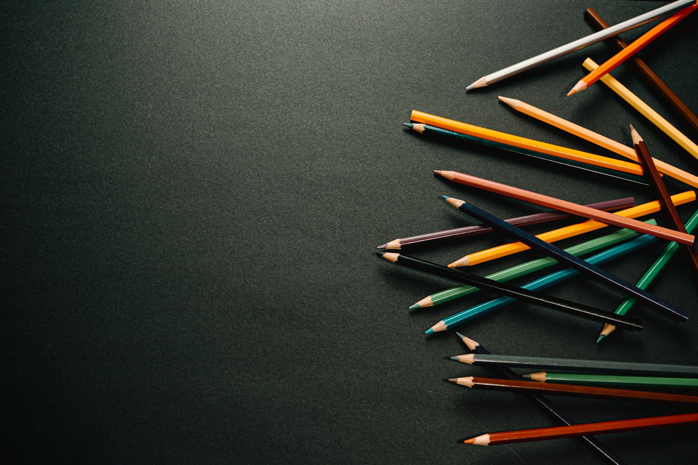 Lápices de colores esparcidos sobre una mesa oscura